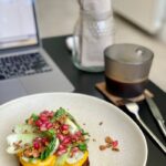 A Toast with Lettuce and Pomegranate and a Cup of Coffee on the Desk next a Laptop